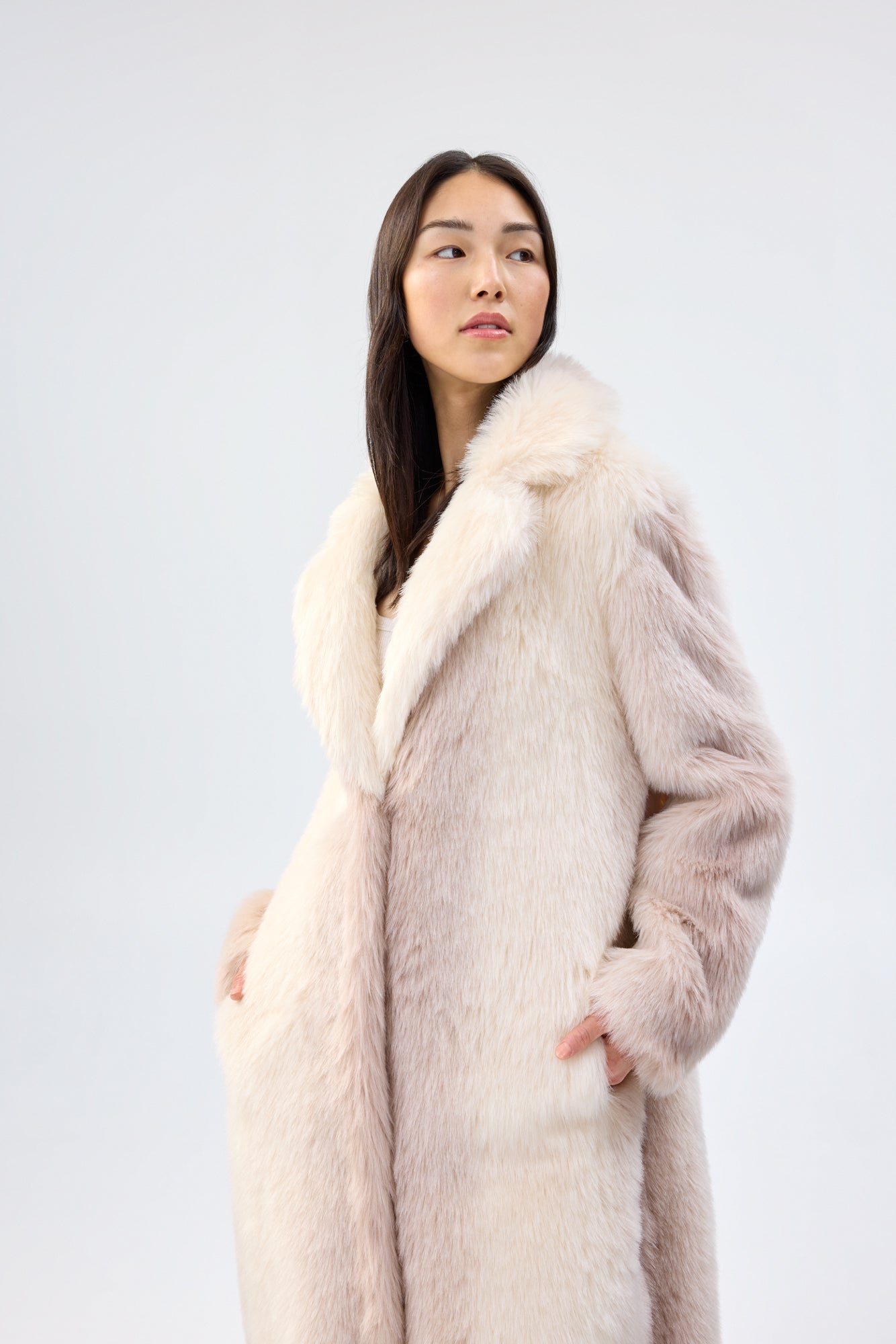 Woman wearing a long faux fur coat with a white background