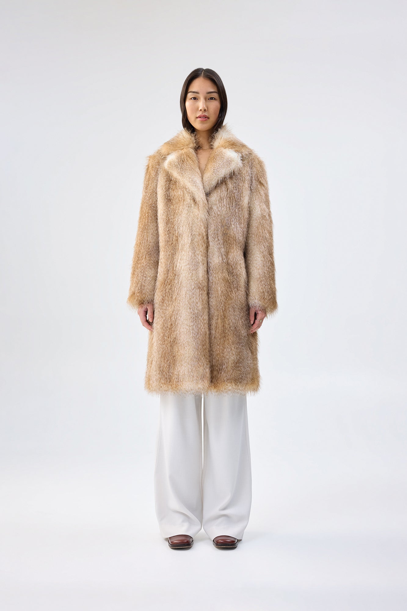 Person wearing a faux fur coat on a white background