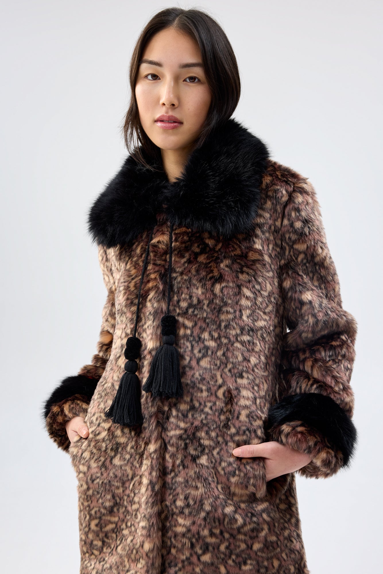 Person wearing a patterned coat with faux fur trim on a white background - close up 