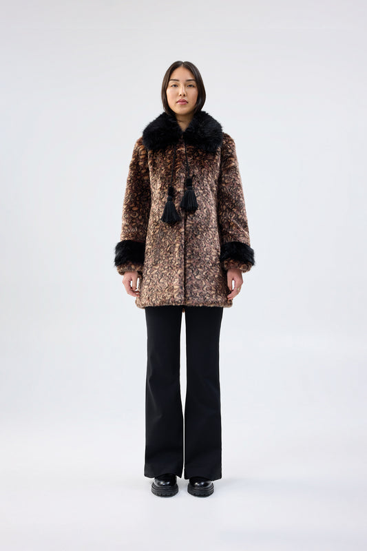 Person wearing a patterned coat with faux fur trim on a white background