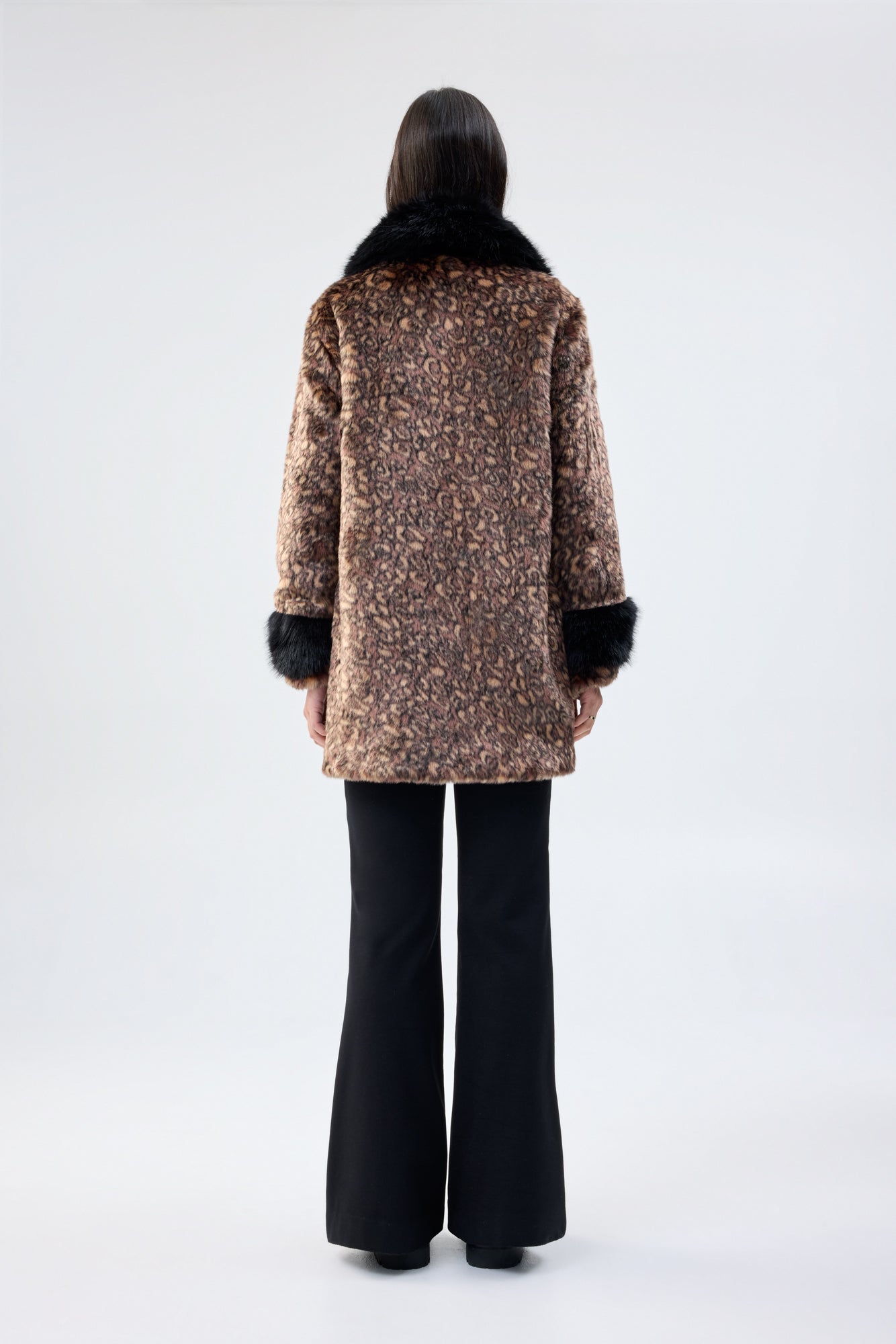 Person wearing a patterned coat with faux fur trim on a white background