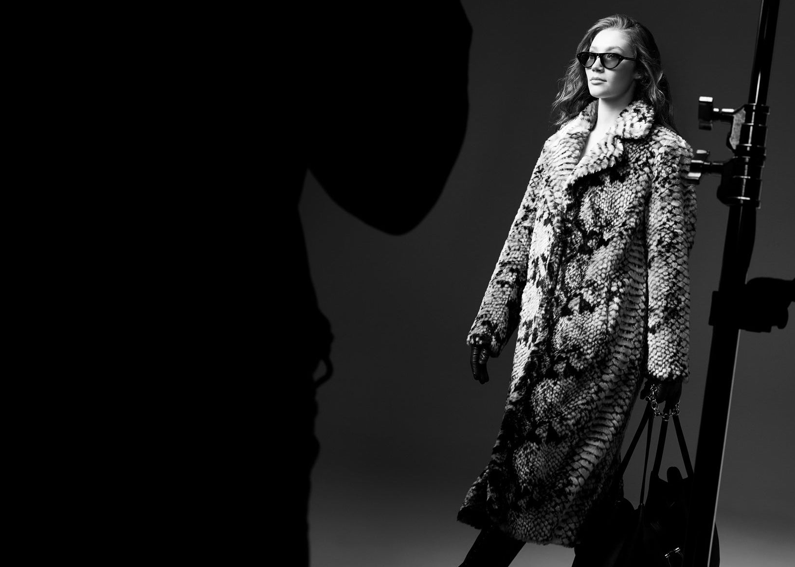 Person wearing a patterned coat and sunglasses in a black and white photo