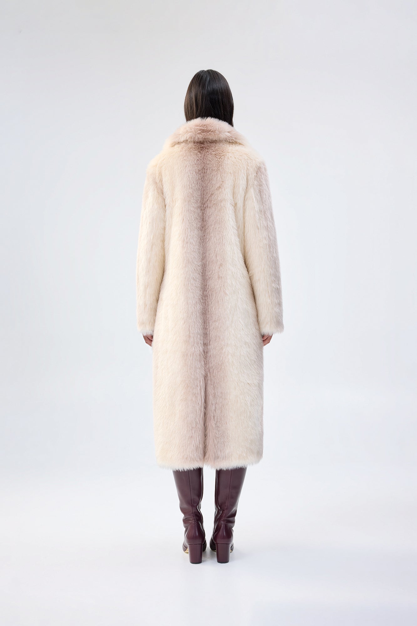 Person wearing a long cream coat on a white background