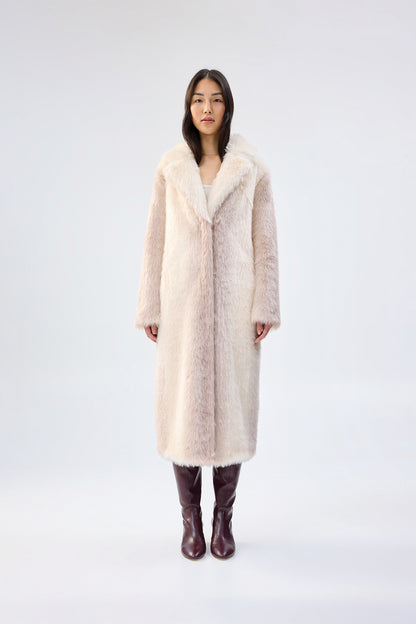 Woman wearing a long cream faux fur coat on a white background