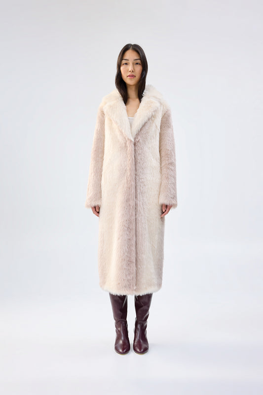 Woman wearing a long cream faux fur coat on a white background