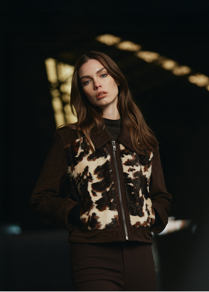 Person wearing a patterned jacket in a dimly lit room
